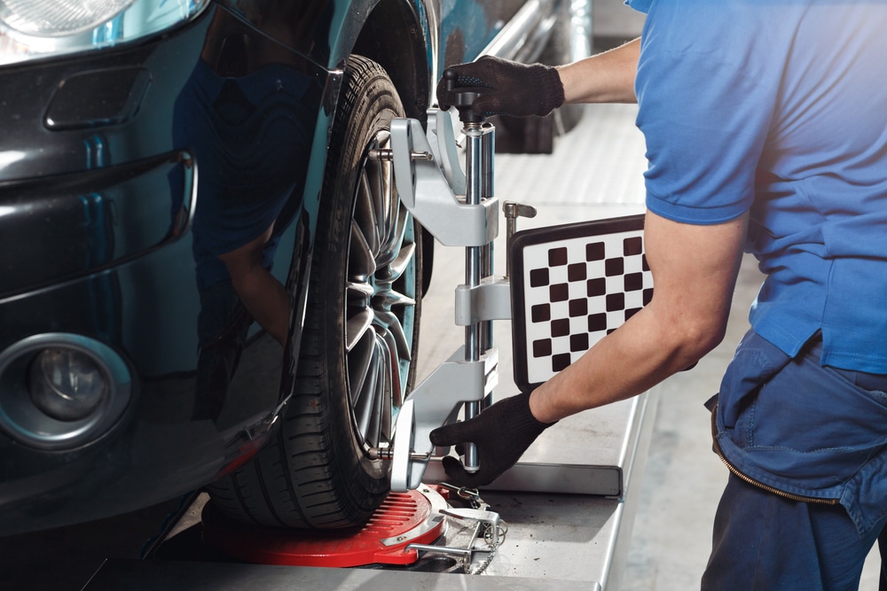Car mechanic using a wheel alignment machine.