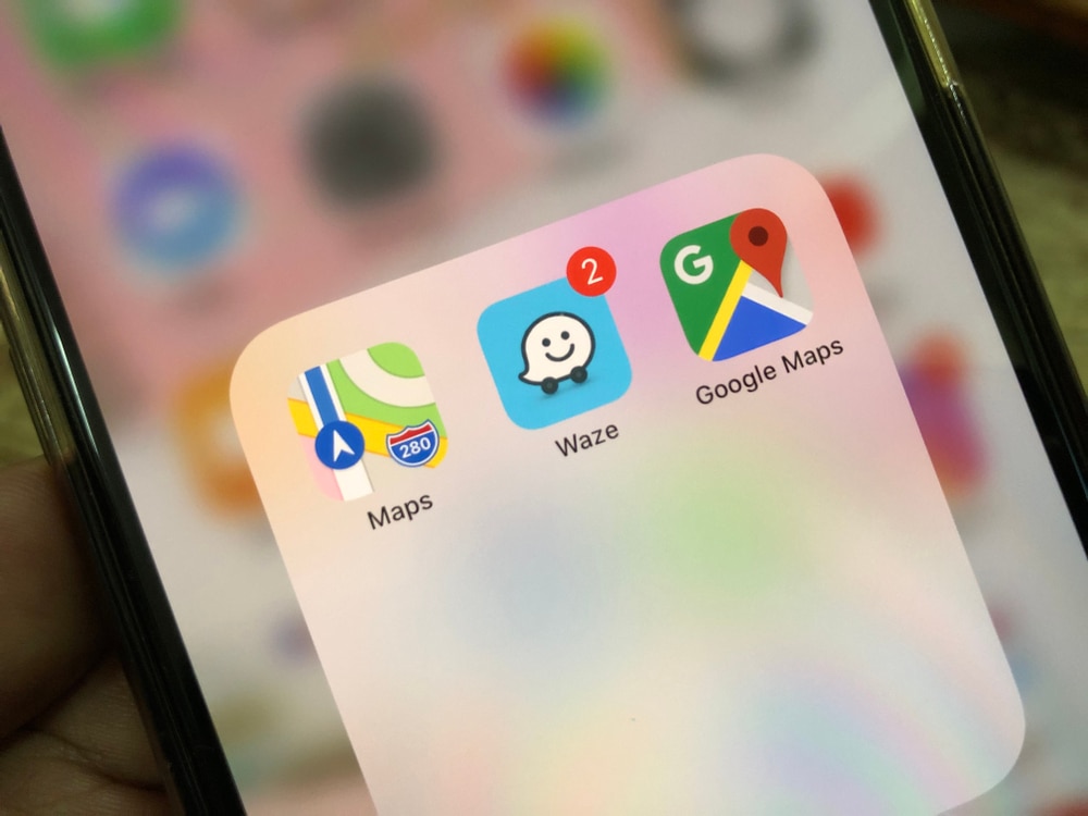 Close up of a smartphone screen displaying navigation apps Waze, Apple Maps, and Google Maps.